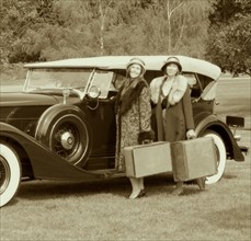 Caucasian women with luggage by vintage car