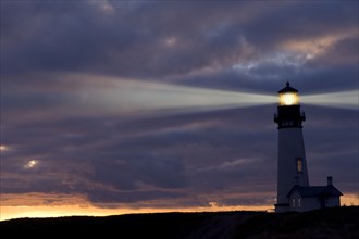 Lighthouse shining against cloudy sky