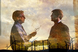 Double exposure of businessmen and wind turbines