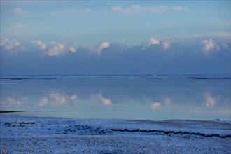 Clouds reflected in still ocean in arctic landscape