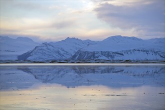 Mountains reflected in still ocean in arctic landscape