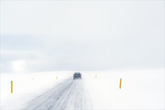 Car driving on rural road in snowy landscape