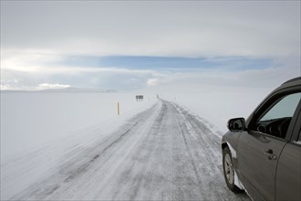 Car driving on rural road in snowy landscape