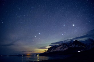 Starry sky over still ocean in arctic landscape