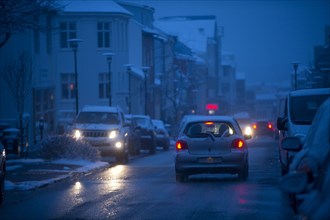 Cars driving on snowy city street at night