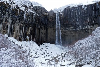 Waterfall and steep cliff in snowy landscape