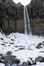 Waterfall and steep cliff in snowy landscape