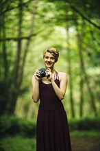 Caucasian woman holding camera in forest