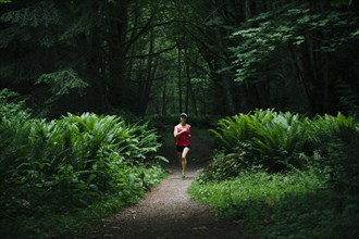 Korean woman running in lush forest