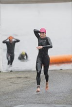Athlete in triathlon removing wet suit after swimming