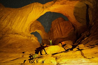 Hiker standing in illuminated rocks at night in Arches National Park