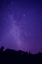 Silhouette of rock formations under starry night sky