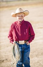 Caucasian boy in cowboy outfit carrying lasso