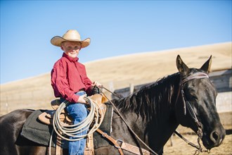 Caucasian boy riding horse on ranch