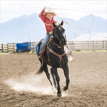 Caucasian boy using lasso on horse at rodeo