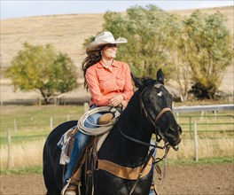 Caucasian woman riding horse on ranch