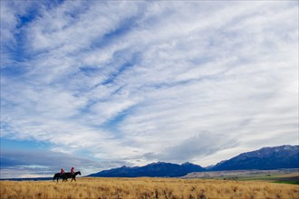 Caucasian herders riding horses in remote field