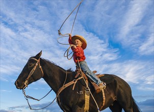 Low angle view of Caucasian boy on horse throwing lasso