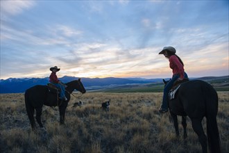 Caucasian mother and son riding horses in remote field