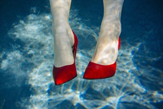 Feet of woman wearing high heels in swimming pool
