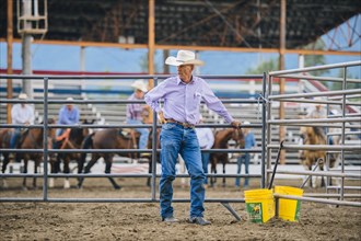 Caucasian cowboy standing at rodeo fence