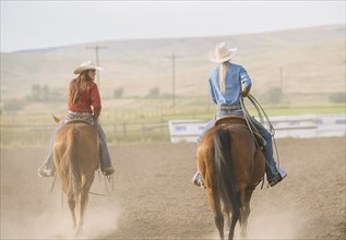 Caucasian cowgirls riding horses on ranch