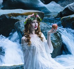 Caucasian woman holding apple at river waterfall