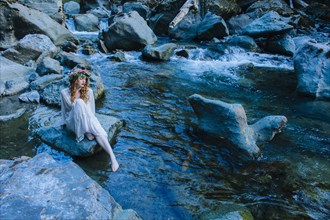 Caucasian woman wearing flower crown on rock at river