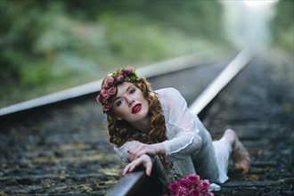 Caucasian woman laying on train tracks
