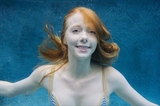 Caucasian woman smiling underwater in swimming pool