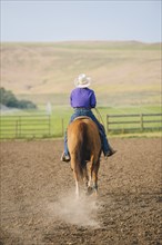 Cowboy riding horseback on ranch