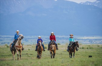Cowboy and cowgirls riding horseback on ranch