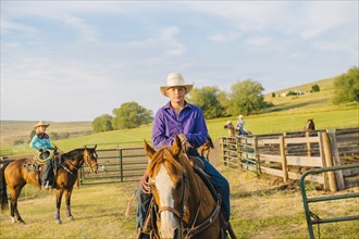 Cowboy riding horseback on ranch