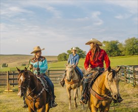Cowgirls riding horseback on ranch