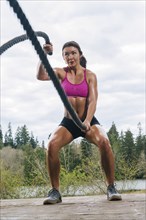 Mixed Race woman working out with heavy ropes