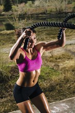 Mixed Race woman working out with heavy ropes