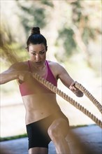 Caucasian woman working out with heavy ropes