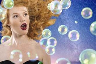 Surprised Caucasian woman watching bubbles floating in starry sky