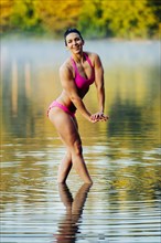 Mixed Race woman flexing muscles in lake