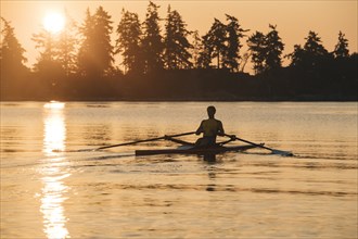 Caucasian man rowing at sunset