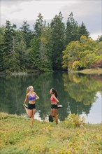 Women stretching legs near lake