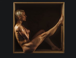 Muscular Caucasian sitting in box covering breasts