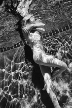Naked Caucasian woman swimming underwater
