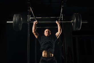 Man lifting heavy barbell in gymnasium