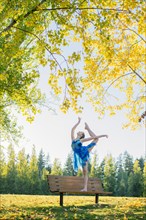 Caucasian ballerina dancing on park bench