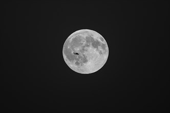 Silhouette of helicopter flying in front of full moon
