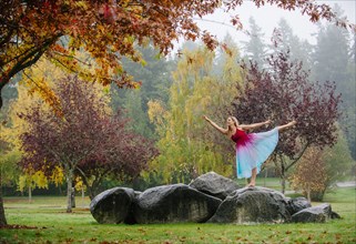 Caucasian ballerina dancing on rocks in park