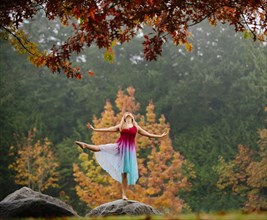 Caucasian ballerina dancing on rock in park
