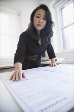 Asian businesswoman looking at blueprints