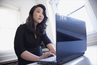 Asian businesswoman typing on laptop